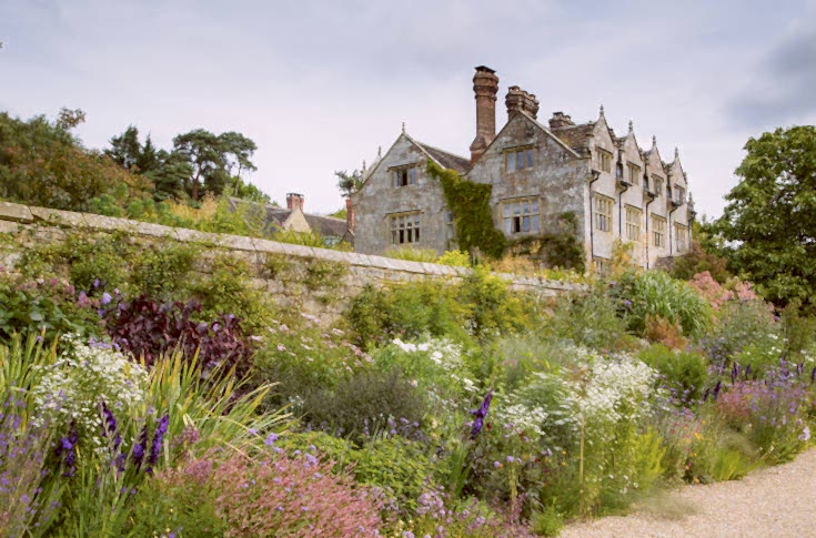 Long border in full bloom with vibrant perennials. Signature gardens at Gravetye Manor West Sussex.