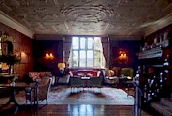 Elegant hotel lounge at Gravetye Manor in West Sussex, featuring luxurious interiors with warm lighting and a cosy, inviting atmosphere.