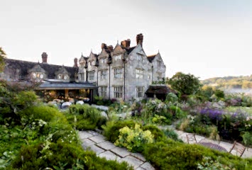 Garden view at Gravetye Manor, West Sussex: traditional stone manor house backed by vibrant planting and serene outdoor seating.