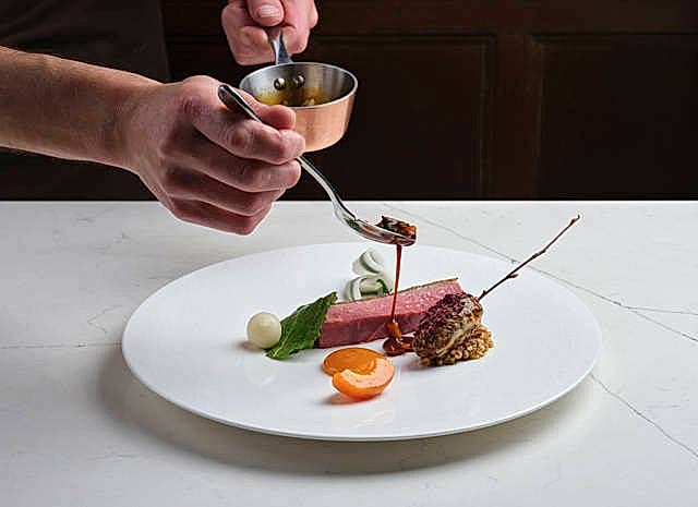 Seared duck with glazed vegetables and rich jus. Fine dining presentation at Gravetye Manor.