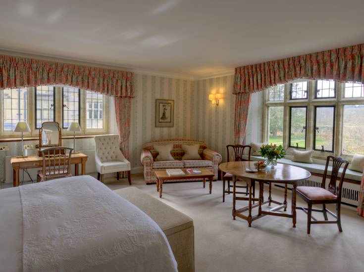 Elegant bedroom with white furniture and draped curtains overlooking the gardens.